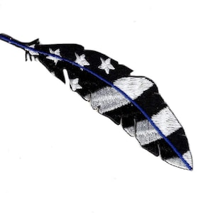 Puede incluir: Pluma negra y blanca con una franja azul en el centro. La pluma está decorada con estrellas blancas.