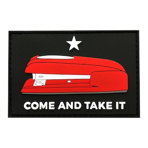 Op de afbeelding: Een zwart-witte patch met een rode nietmachine en de tekst "COME AND TAKE IT".