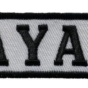 May include: Black and white embroidered patch with the word "MAYANS" in all caps.