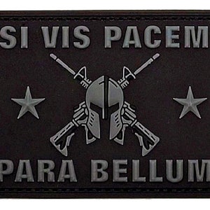 Peut inclure: Patch tactique noir avec du texte brodé gris "Si Vis Pacem Para Bellum" et une image stylisée grise d'un casque avec des fusils croisés et deux étoiles.