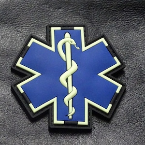 May include: A blue and white star of life patch with a white snake and staff symbol in the center. The patch has a black border.