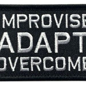 Puede incluir: Parche bordado negro con las palabras "IMPROVISE ADAPT OVERCOME" en blanco. El parche rectangular tiene un borde negro. Ideal para chaquetas, bolsos u otras prendas.