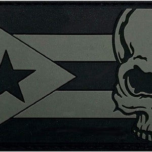 May include: A rectangular patch featuring the Puerto Rican flag design with a skull graphic. The flag is in shades of gray and black, with a star and stripes. The skull is on the right side of the patch.