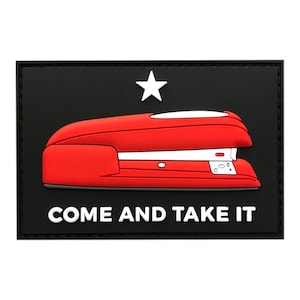 Op de afbeelding: Een zwarte patch met een witte ster en een rode nietmachine. De tekst "COME AND TAKE IT" staat onder de nietmachine.