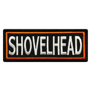 May include: Black embroidered patch with an orange border. The patch says "SHOVELHEAD" in white lettering.