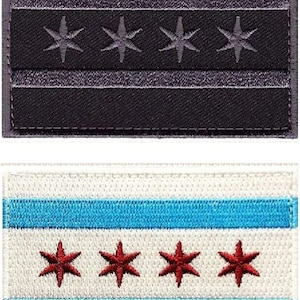 Può includere: Due toppe ricamate con la bandiera di Chicago. La toppa superiore è nera con stelle e strisce bianche. La toppa inferiore è bianca con strisce blu e stelle rosse.