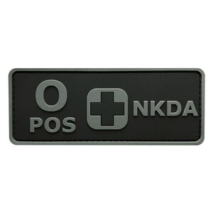 May include: A black rectangular patch with a white medical cross, the letters "O POS" and the text "NKDA" in gray.