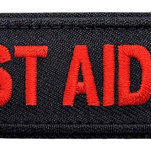 May include: Black fabric patch with red embroidered text that reads "FIRST AID KIT".