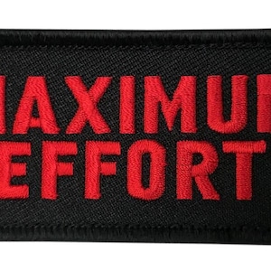 以下が含まれることがあります： 「MAXIMUM EFFORT」の文字が赤色で刺繍された黒色の長方形パッチ。 パッチには黒い縁取りがあり、衣服やギアに縫い付けたり、取り付けたりするように設計されています。