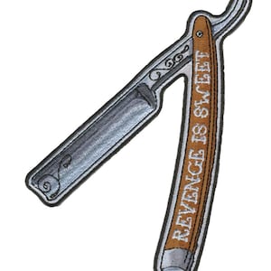 May include: A brown and silver straight razor with a wooden handle. The handle has the text "Revenge is sweet" written on it.