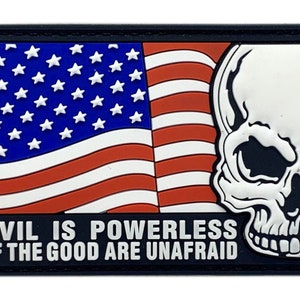 May include: A black and white patch with an American flag and a skull. The text reads "Evil is powerless if the good are unafraid."