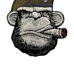 May include: Embroidered patch of a monkey's face, wearing an olive green beret and smoking a cigar. The patch has a white background. The monkey's face is detailed with white and black thread.