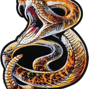 May include: A coiled rattlesnake with a bright orange, yellow, and white pattern. The snake's mouth is open, revealing sharp fangs. The snake is on a black background.