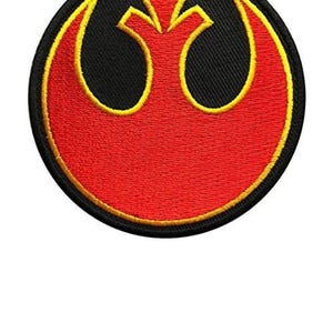 May include: A red and yellow embroidered patch featuring the Rebel Alliance symbol from Star Wars. The symbol is a white bird with wings outstretched, set against a black background.