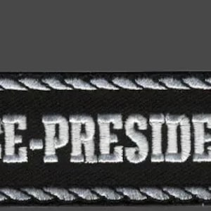 May include: Black and white embroidered patch with a white rope border. The patch says "VICE-PRESIDENT" in white lettering.