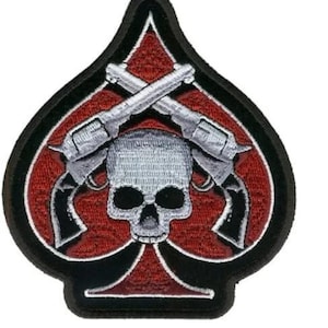 May include: A black and red embroidered patch with a skull and crossbones. The skull is white and the crossbones are silver. The patch is shaped like a spade.