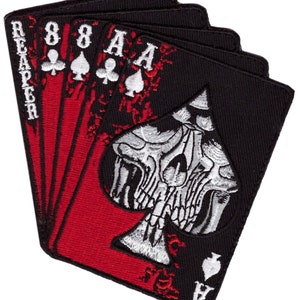 Può includere: Una toppa ricamata nera e rossa con un teschio con un design a picche. La toppa ha le parole "Reaper" e "8".