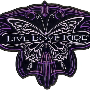 Puede incluir: Parche bordado en morado y blanco con un diseño de mariposa y el texto "Live Love Ride".