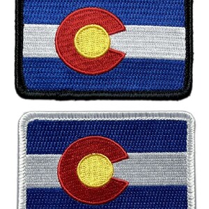 May include: Two embroidered patches of the Colorado state flag. The top patch has a black border and the bottom patch has a white border.