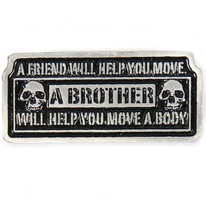 May include: A silver metal pin with a black background and white skull graphics. The text reads "A friend will help you move. A brother will help you move a body."