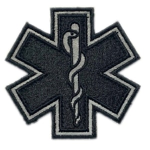 Peut inclure: Un écusson brodé noir et argent avec une étoile à six branches et un serpent enroulé autour d'un bâton. L'écusson est couramment utilisé comme symbole des services médicaux d'urgence.