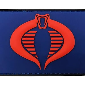 May include: An embroidered patch featuring the Cobra symbol from the G.I. Joe cartoon, in blue and red.