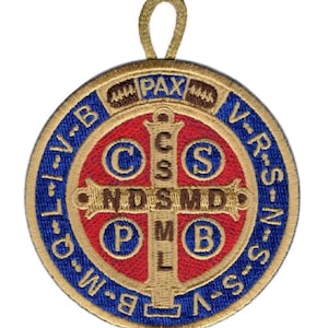 Puede incluir: Un parche bordado circular con el diseño de una medalla de San Benito y un lazo dorado en la parte superior. El centro muestra una cruz roja con letras doradas C S M L y N D S M D, rodeadas por círculos azules con las letras C S P B. El borde azul exterior contiene el texto dorado V R S N S M V S M Q L I V B.