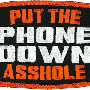 May include: Black and orange embroidered patch with the text "PUT THE PHONE DOWN ASSHOLE".