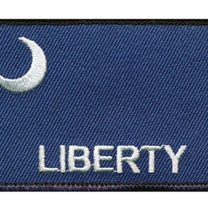 May include: A blue fabric patch with a white crescent moon and the word "LIBERTY" embroidered in white.