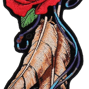 Peut inclure: Patch brodée thermocollante représentant une rose rouge avec des feuilles vertes et deux plumes brunes avec des accents bleus et violets.