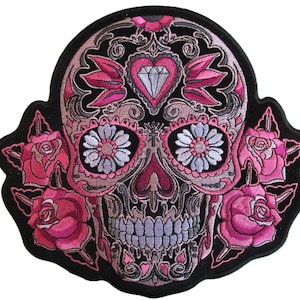 Op de afbeelding: Geborduurde roze en zwarte suiker schedel patch met rozen. De schedel heeft een diamant op het voorhoofd en bloemmotieven rond de ogen.