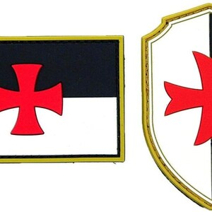 May include: Two patches: a rectangular one and a shield-shaped one. Both feature a red cross on a black and white background. The rectangular patch has a gold border, while the shield has a gold border.