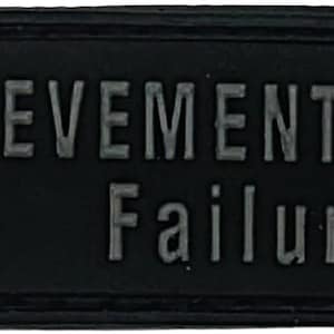 Puede incluir: Parche rectangular negro con las palabras "ACHIEVEMENT EARNED" encima de "Failure" en letras grises. Un gráfico verde y gris de un candado está en el lado izquierdo. El parche tiene un borde cosido.