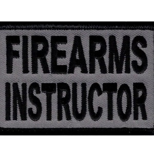 Könnte beinhalten: Schwarzer und grauer gestickter Aufnäher mit dem Text "FIREARMS INSTRUCTOR" in Weiß.