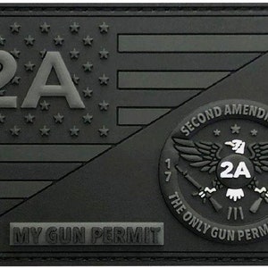 Puede incluir: Un parche negro y gris con un diseño de bandera estadounidense y un círculo con el texto "Second Amendment" y "The Only Gun Permit I Need". El círculo también presenta un águila calva con el texto "2A" en su pecho.