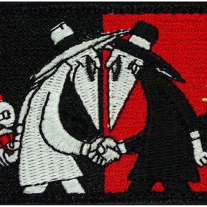 May include: Embroidered patch featuring two figures in black and white, shaking hands. The figure on the left is holding a red dynamite stick, while the figure on the right is holding a black dynamite stick. The background is split in half, with black on the left and red on the right.