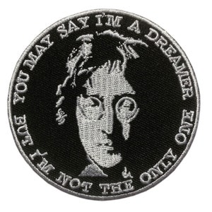 Può includere: Una toppa ricamata in bianco e nero con un ritratto di John Lennon e il testo "You may say I'm a dreamer, but I'm not the only one".