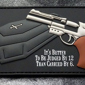 May include: Black and white patch with a gun and a coffin. The text reads "It's Better To Be Judged By 12 Than Carried By 6."