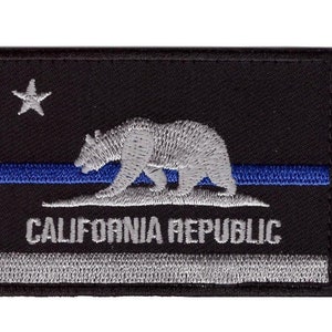 May include: Black embroidered patch with a white outline of a bear and a blue stripe. The text "CALIFORNIA REPUBLIC" is embroidered in white below the bear.
