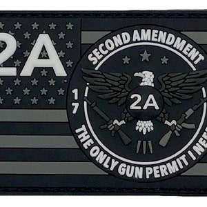 May include: A black and gray patch featuring the American flag with the text "2A" and a circular emblem with an eagle, guns, and the text "SECOND AMENDMENT THE ONLY GUN PERMIT I NEED".