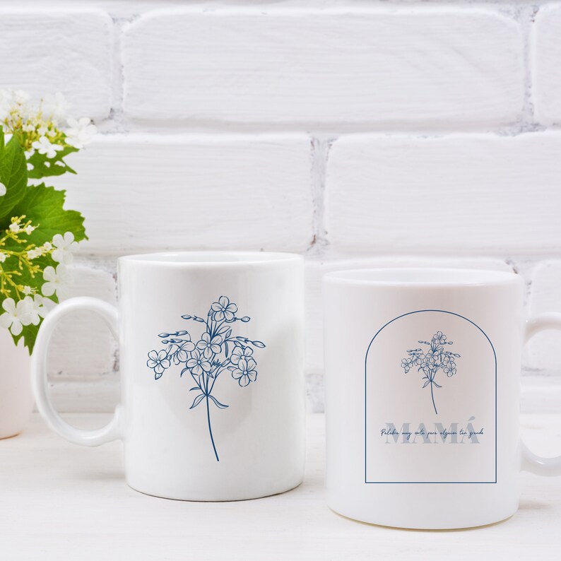 Pode incluir: Duas canecas de cer&acirc;mica branca com um design floral azul. Uma caneca tem a palavra "MAMA" com o texto "Feliz dia m&atilde;e por algu&eacute;m t&atilde;o especial" embaixo.