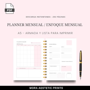 Puede incluir: Un planificador mensual A5, encuadernado en espiral, con un dise&ntilde;o rosa y blanco. Incluye un calendario mensual y secciones para el enfoque semanal. Tambi&eacute;n incluye un bol&iacute;grafo negro y dorado. Texto: "PLANNER MENSUAL / ENFOQUE MENSUAL".