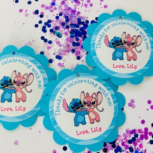 K&ouml;nnte beinhalten: Drei blaue und wei&szlig;e Geschenkanh&auml;nger mit gewelltem Rand. Jeder Anh&auml;nger zeigt ein Cartoon-Bild von Stitch und Angel aus dem Disney-Film Lilo & Stitch. Der Text auf den Anh&auml;ngern lautet "Danke, dass du mit mir gefeiert hast! Liebe, Lily."