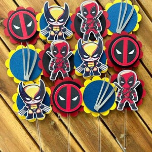 May include: A set of 10 cupcake toppers featuring characters from the Marvel comics, Deadpool and Wolverine. The toppers are printed on cardstock and have a scalloped edge. The characters are depicted in a cartoon style and are wearing their signature costumes. The toppers are perfect for a superhero-themed party.