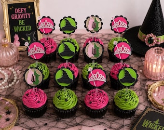 Può includere: Cupcake con glassa rosa e verde, sormontati da decorazioni a forma di cappello da strega e diademi. L'immagine include anche un cappello da strega e un cartello incorniciato con la scritta "Defy Gravity Be Wicked".