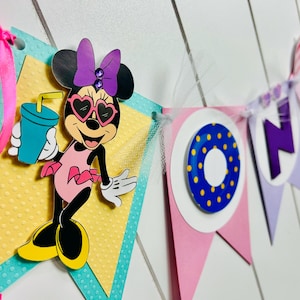 May include: A pink, purple, and blue banner with the word "ONE" in purple letters. The banner features a Minnie Mouse character wearing sunglasses and a pink swimsuit, holding a blue drink with a straw. The banner is decorated with yellow polka dots and a blue and yellow ring.
