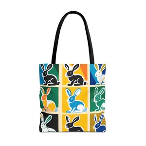 Könnte beinhalten: Eine schwarze Tragetasche mit einem farbenfrohen Design, das neun Kaninchen in verschiedenen Farben und Posen zeigt. Die Kaninchen sind in einem Rastermuster auf der Tasche angeordnet.