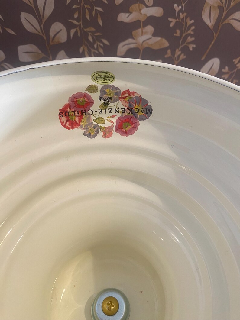 May include: Cream-colored enamelware basin with a floral decal featuring red, pink, and purple flowers. The words "MACKENZIE-CHILDS" are printed on the side. A small sticker reads "MADE IN CHINA".