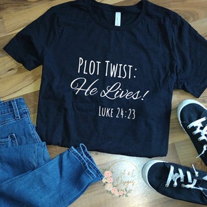May include: Black t-shirt with white text that reads "Plot Twist: He Lives!" and "Luke 24:23".