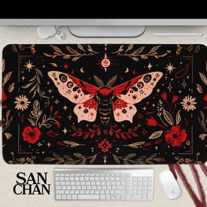 May include: Black mouse mat with a red and gold moth design. The moth has intricate details and is surrounded by floral patterns. The mouse mat is rectangular and has a smooth surface.